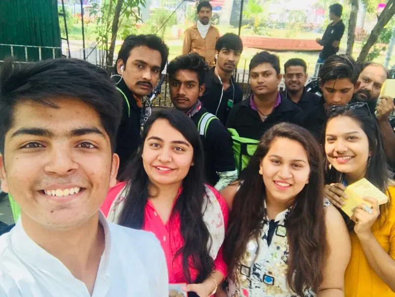 A selfie of smiling volunteers with delivery riders on Diwali morning