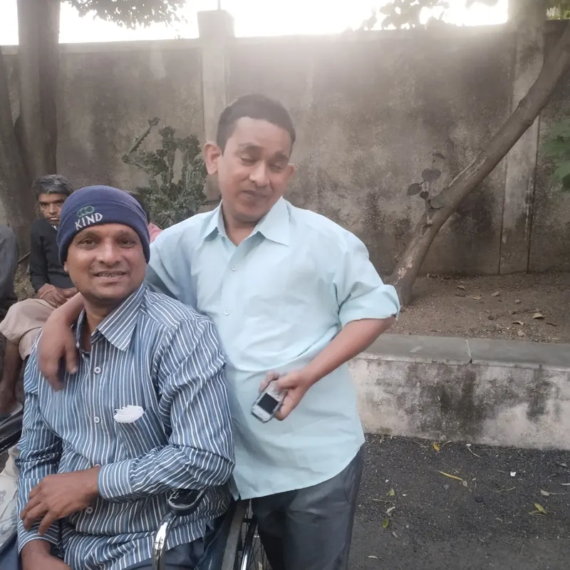 Two men smiling together, one of them seated in a wheelchair