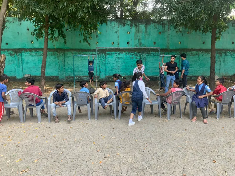Children playing musical chairs with volunteers at the school in Indore