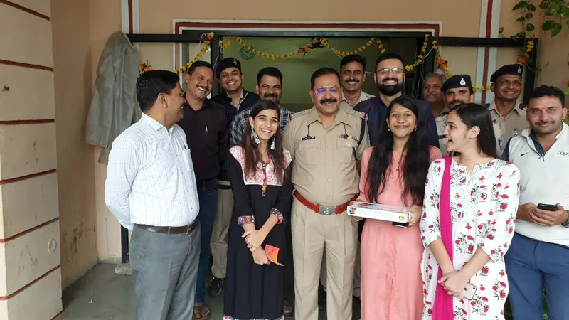 Laughing police officers with three volunteers holding a box of Diwali sweets