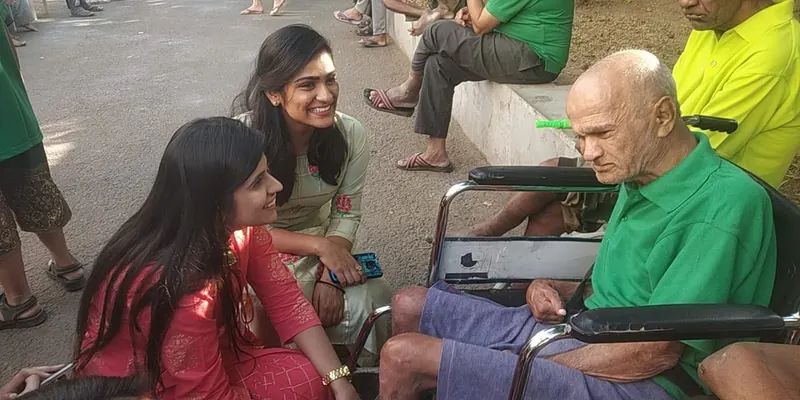 Two volunteers chatting warmly with a senior resident in a wheelchair